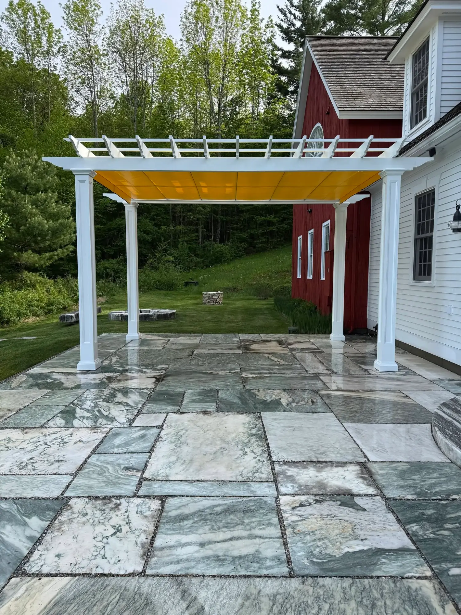 Pergola with yellow retractable shade canopy over a natural stone patio